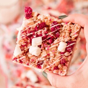 A hand holding up a piece of raspberry granola.