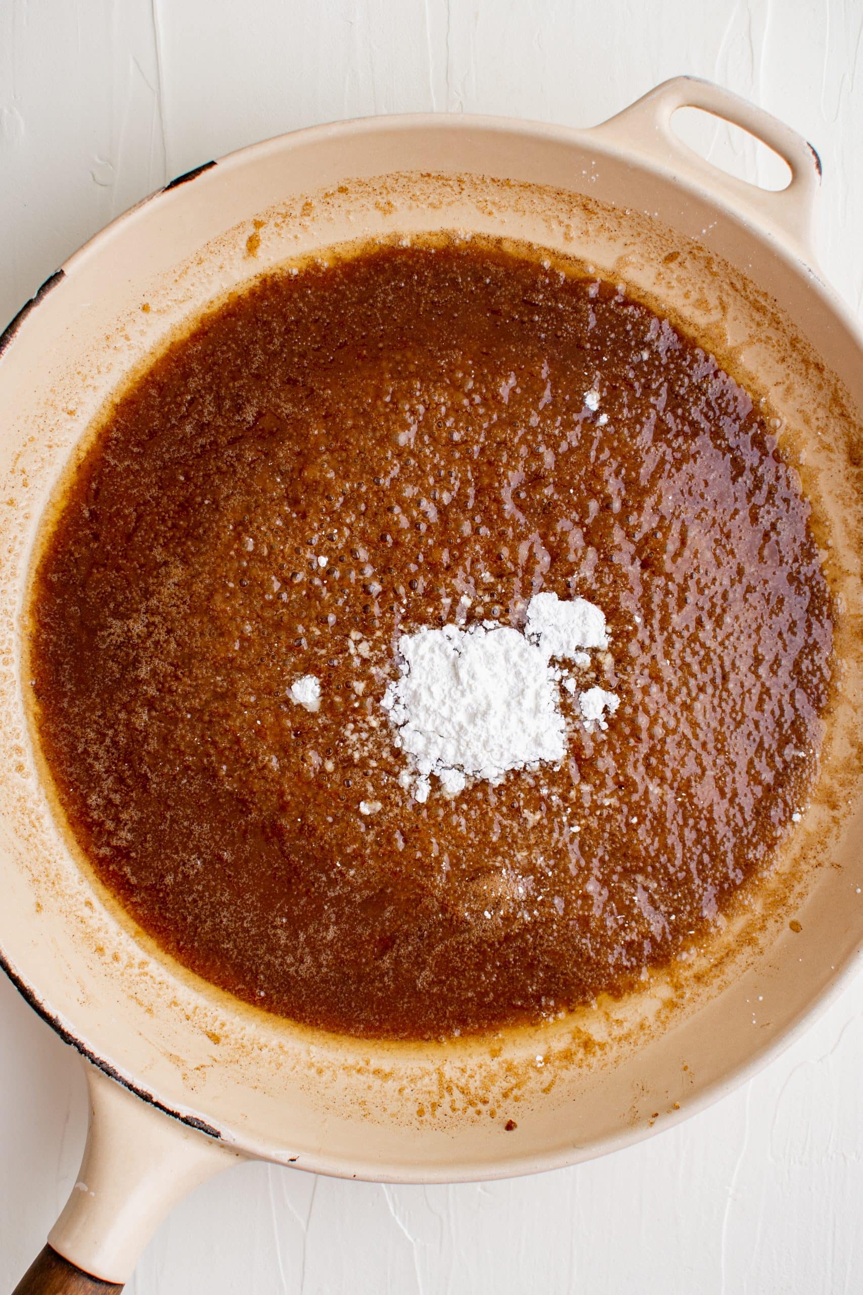A skillet filled with brown sugar and powdered sugar-glazed carrots.