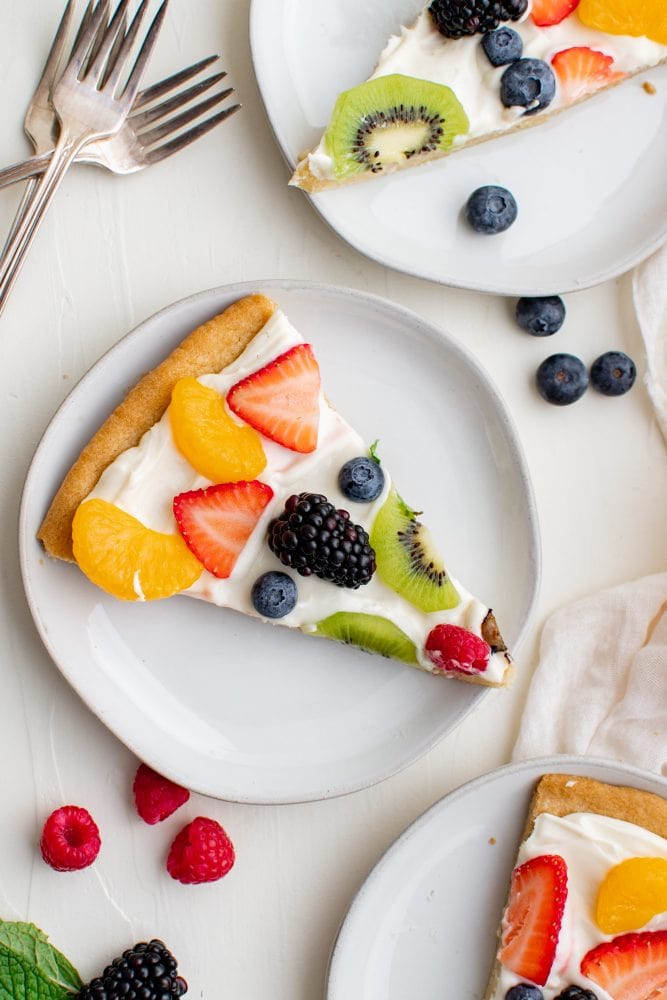 two slices of fruit cookie with cream and fruit arranged on top of the cream