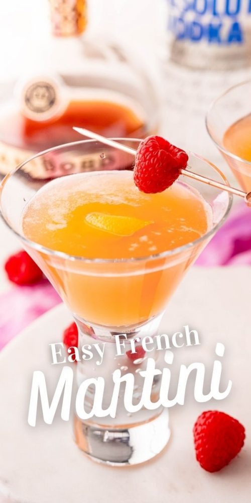 orange martini in a glass with a raspberry stuck across it