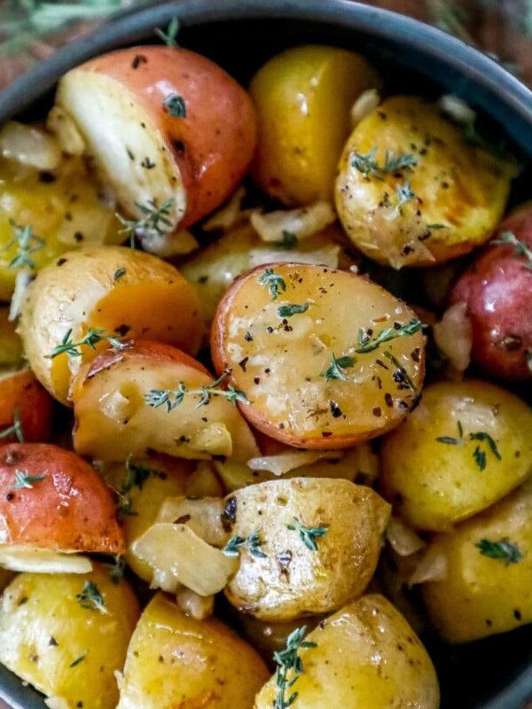 picture of roasted potatoes with butter, spices, and sprigs of fresh thyme in a bowl