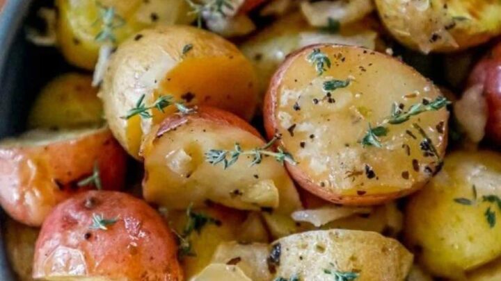 picture of garlic butter roasted potatoes in a blue bowl with herbs on top