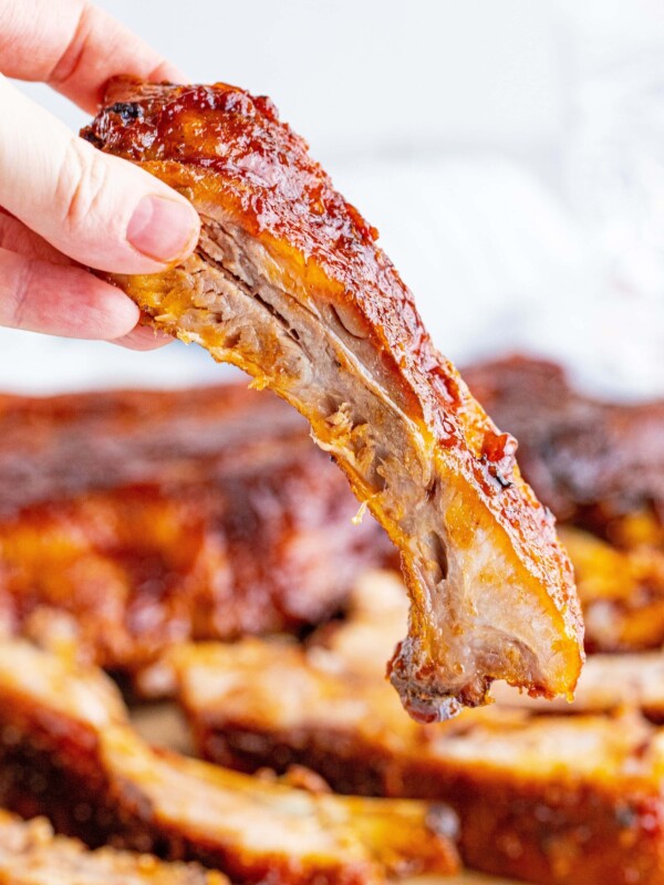 The Best Grilled Ribs Recipe Story featuring a person holding a piece of BBQ ribs.