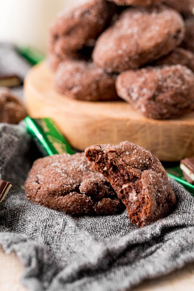 chocolate cookies stacked on a board with andes mints all over