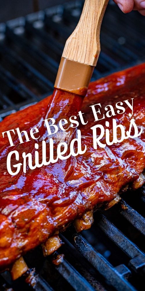 picture of hand basting a rack of ribs with bbq sauce on a grill