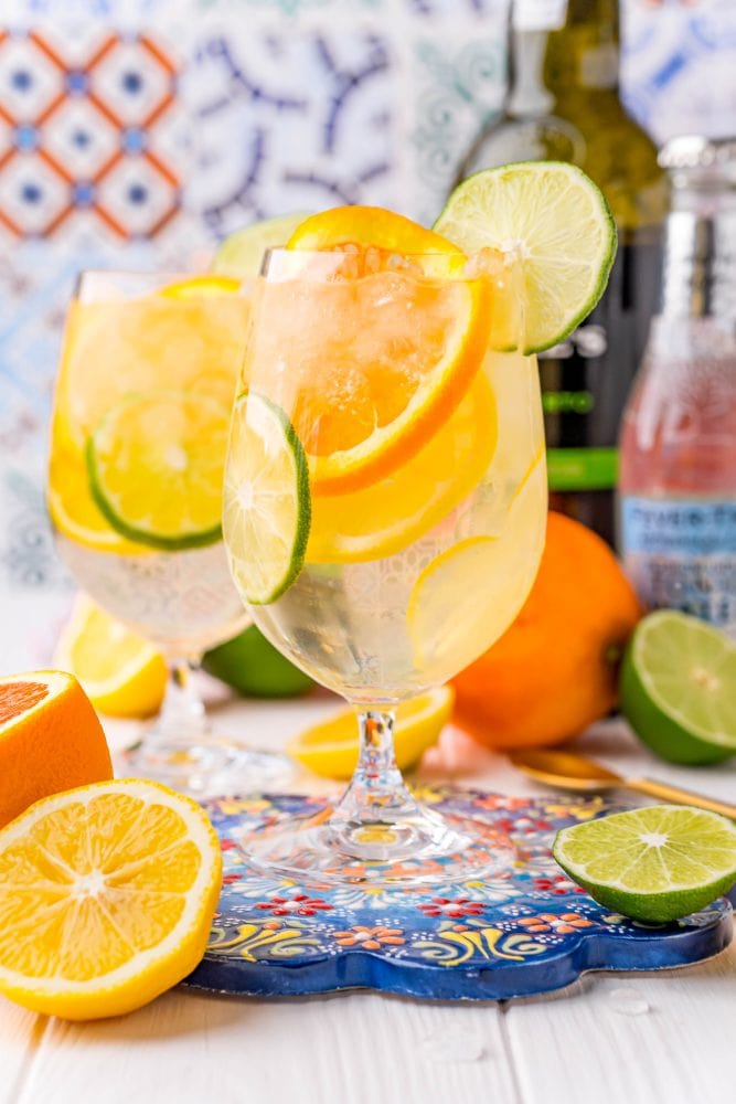 picture of a wine goblet with slices of citrus, ice, port, and tonic on a table