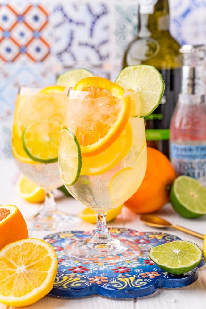 picture of a wine goblet with slices of citrus, ice, port, and tonic on a table