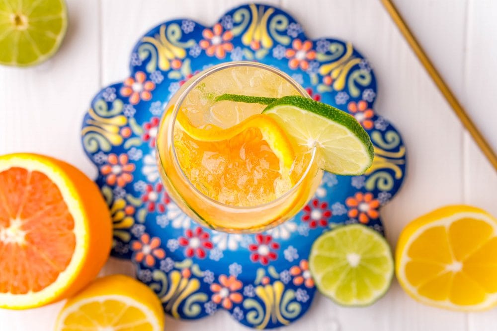 picture of a wine goblet with slices of citrus, ice, port, and tonic on a table