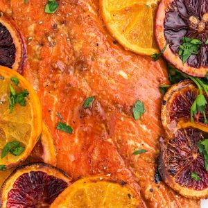 Grilled salmon with orange slices on a plate.