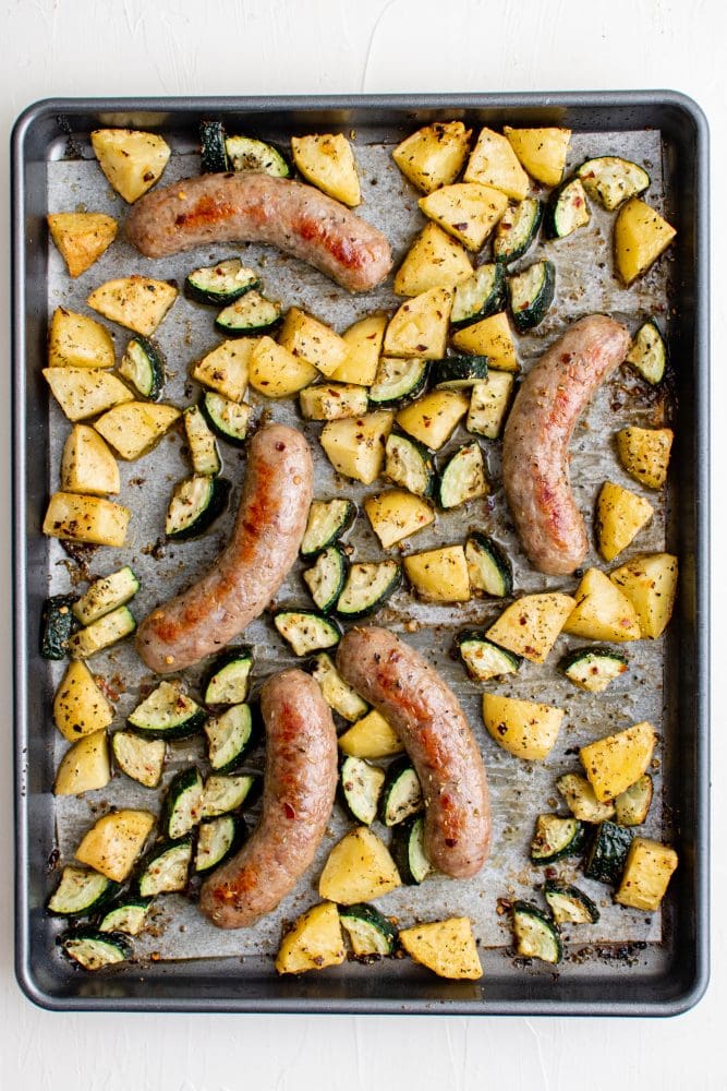 picture of sausage potatoes and zucchini on a baking sheet