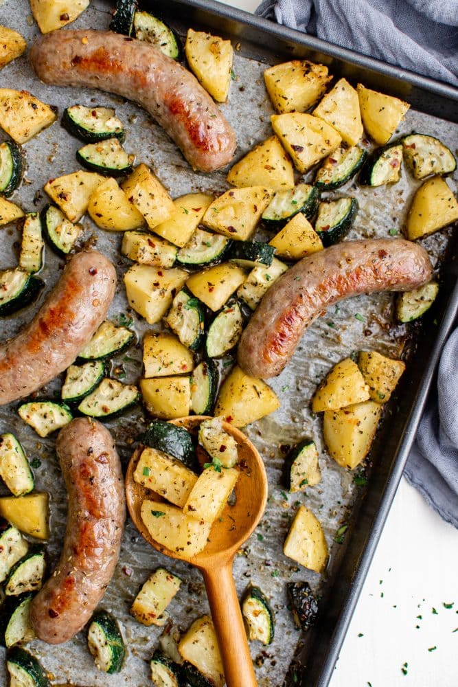 picture of sausage potatoes and zucchini on a baking sheet