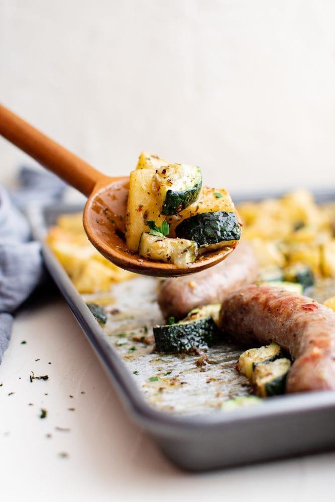 picture of sausage potatoes and zucchini on a baking sheet