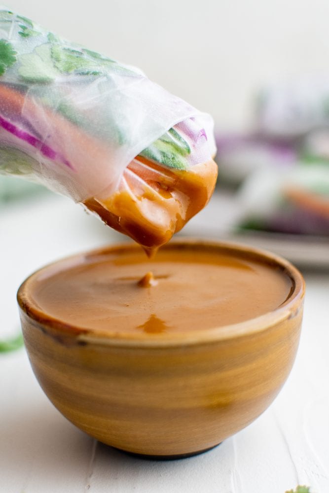 picture of spring roll being dipped into peanut sauce