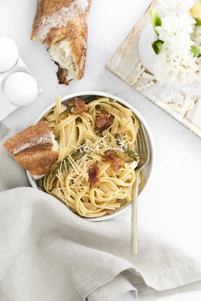 picture of a bowl with noodles, asparagus, parmesan cheese, bacon, and carbonara sauce