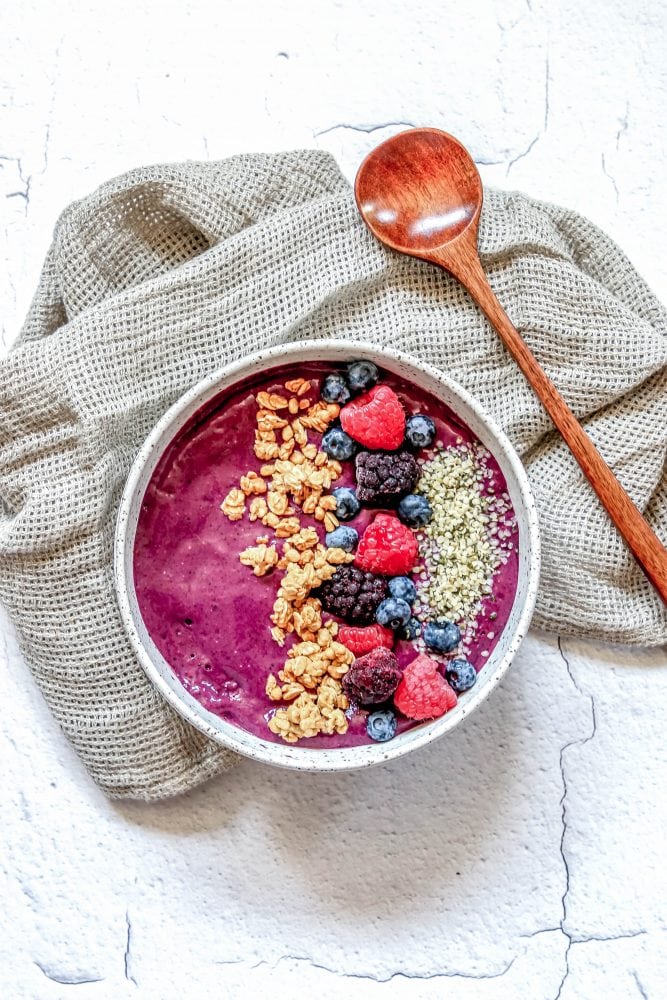 picture of berry smoothie bowl with raspberries, granola, blackberries, blueberries, and hemp hearts on top 