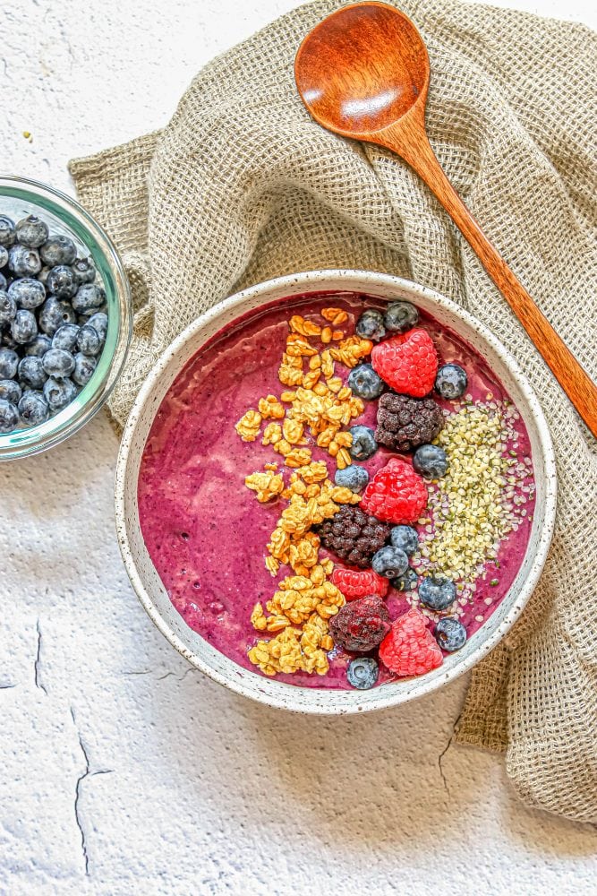 picture of berry smoothie bowl with raspberries, granola, blackberries, blueberries, and hemp hearts on top 