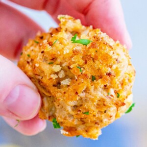 A person displaying a mini crab cake appetizer.