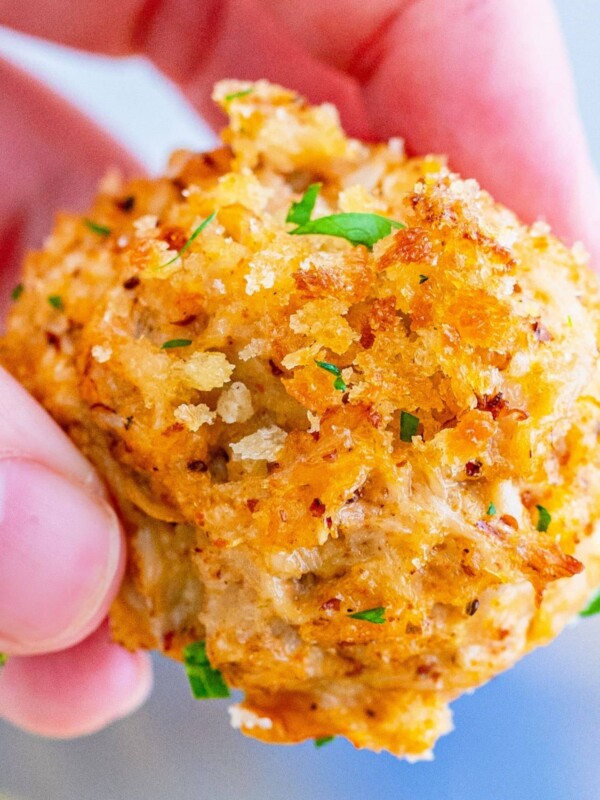 A person displaying a mini crab cake appetizer.