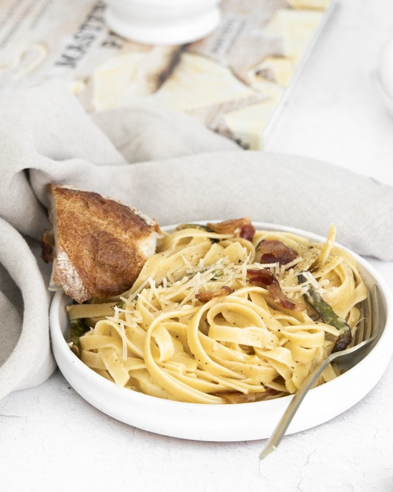 picture of a bowl with noodles, asparagus, parmesan cheese, bacon, and carbonara sauce