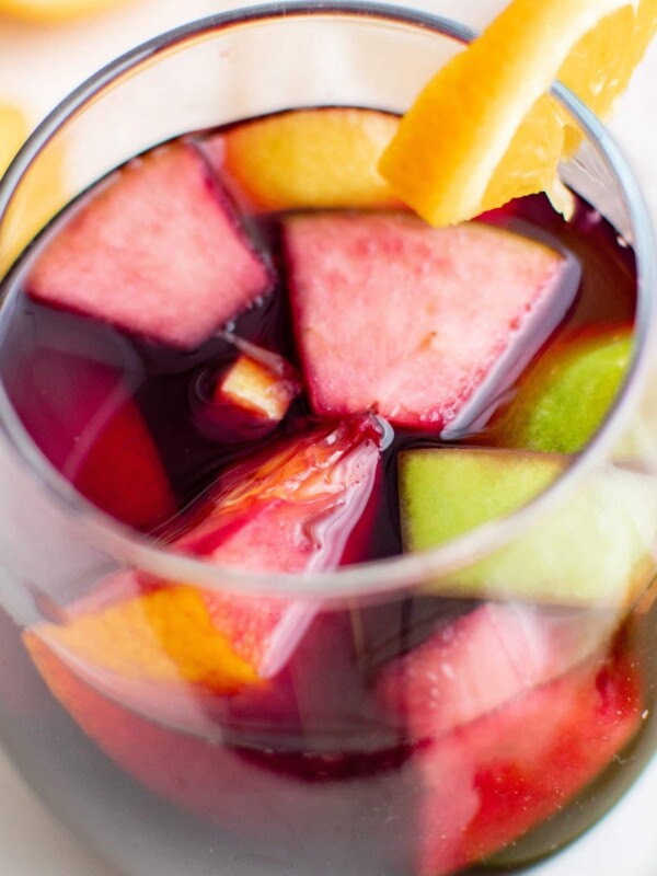 A glass of Easy Red Sangria with fruit slices in it.