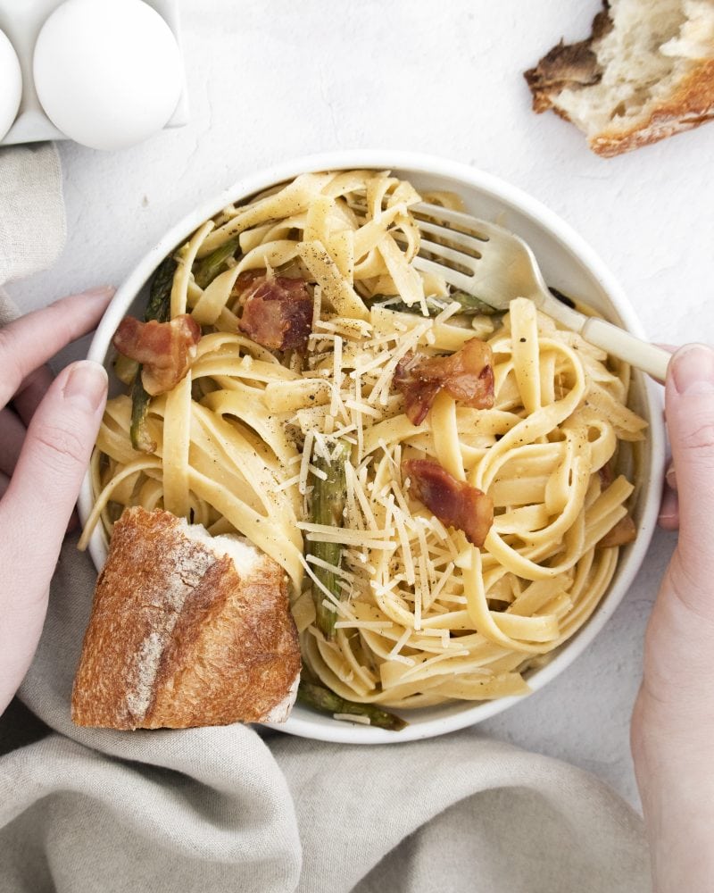 picture of a bowl with noodles, asparagus, parmesan cheese, bacon, and carbonara sauce