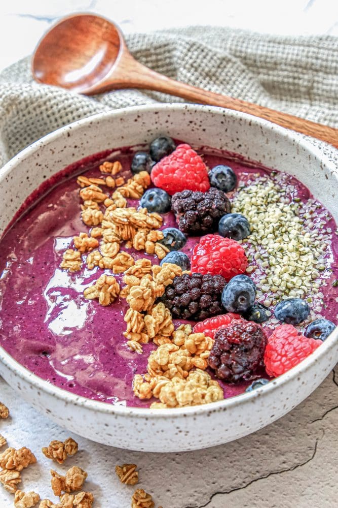 picture of berry smoothie bowl with raspberries, granola, blackberries, blueberries, and hemp hearts on top 