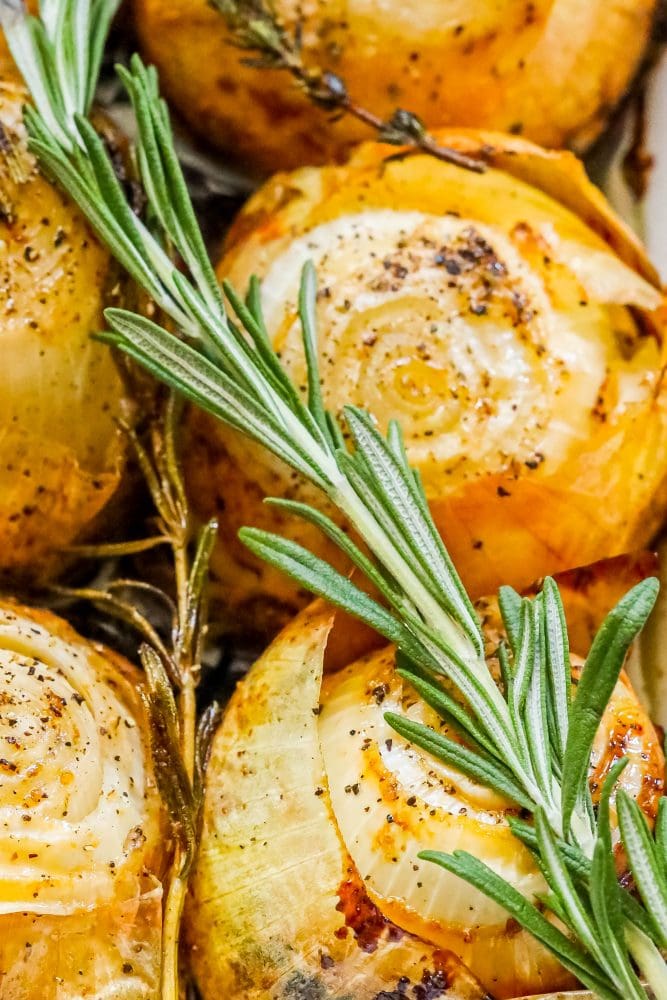picture of whole roasted onions in a tray with pepper and rosemary 