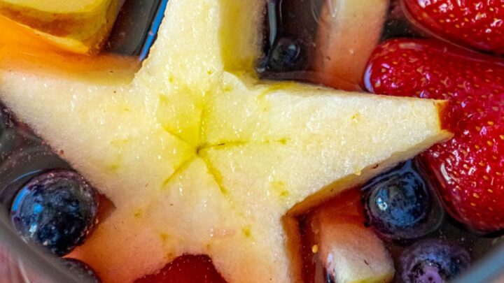 picture of patriotic fruit punch in a pitcher with strawberries, blueberries, and star shaped apple slices