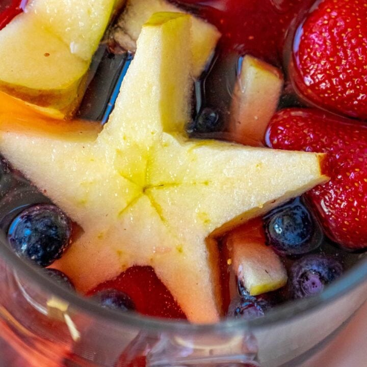 picture of patriotic fruit punch in a pitcher with strawberries, blueberries, and star shaped apple slices