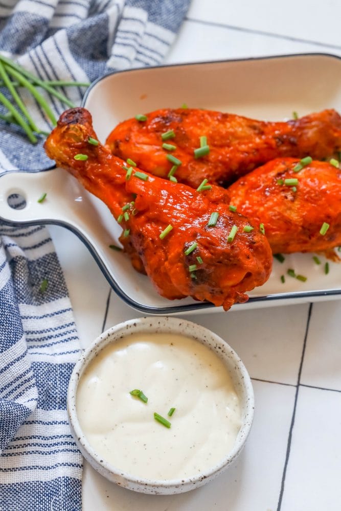 chicken drumsticks with red buffalo sauce on them dip on the side