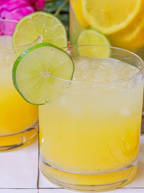 Two glasses of sparkling pineapple lemon and limeade with flowers.