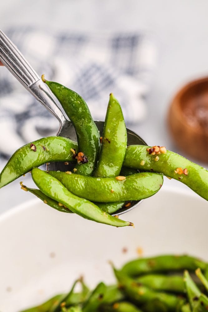 edamame beans on a spoon with spices on it. 