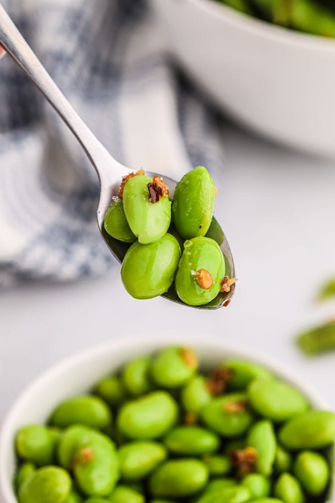 edamame beans in a bowl with spices on it. 