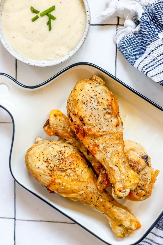 picture of chicken drumsticks on a white baking dish 