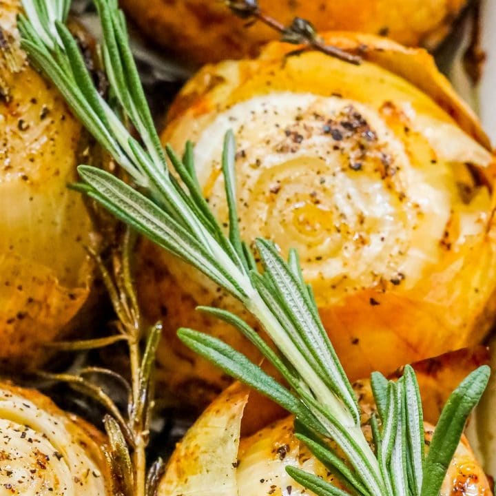 picture of whole roasted onions in a tray with pepper and rosemary