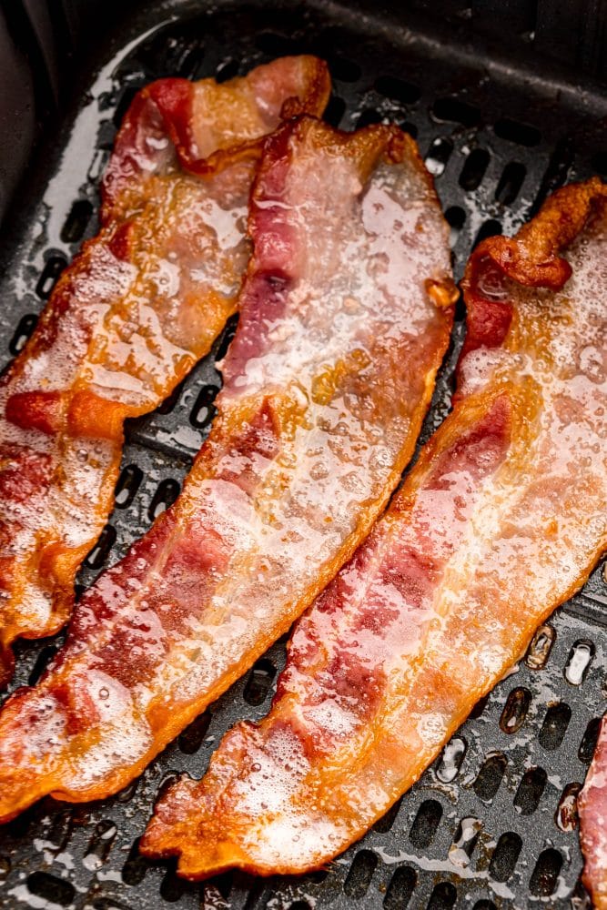 bacon strips cooking in an air fryer basket