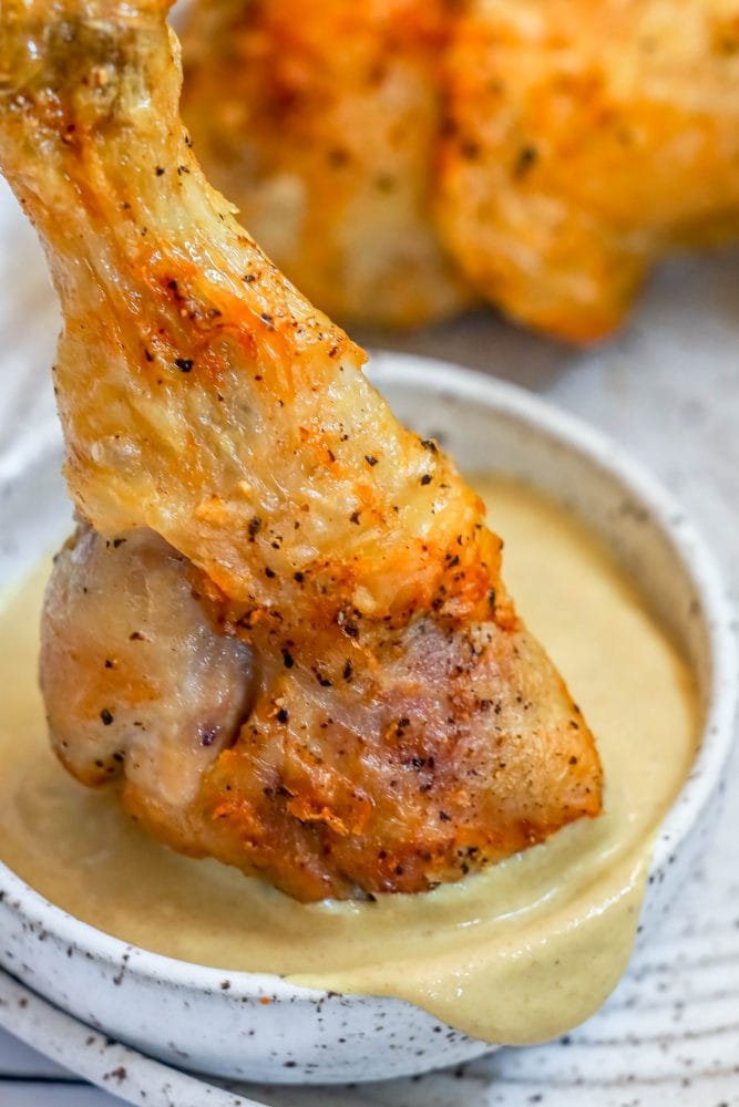 picture of chicken drumstick being dipped into mustard