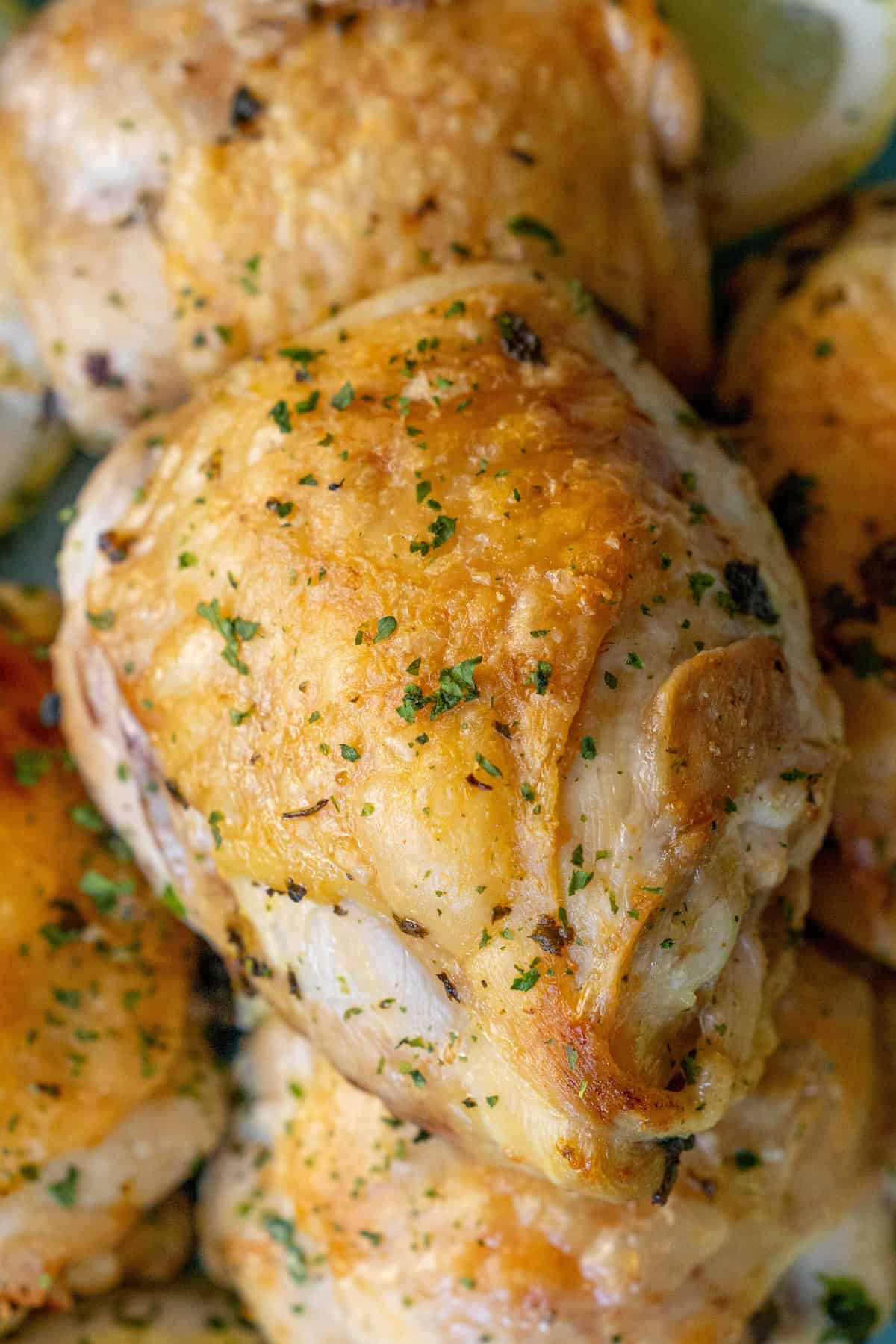 Close-up of seasoned and cooked chicken thighs garnished with herbs, showcasing an easy air fryer lemon chicken recipe.