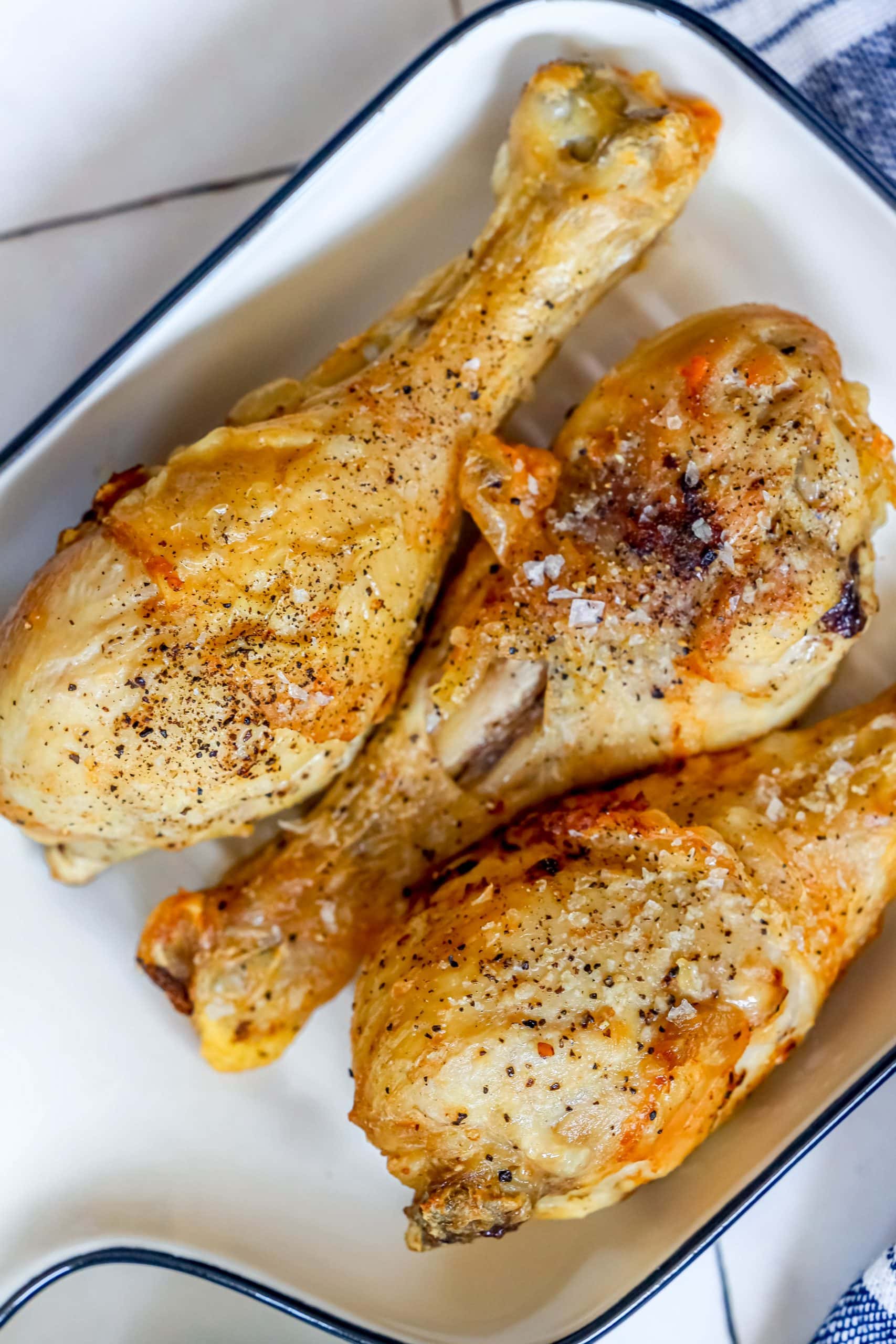 Crunchy baked chicken drumsticks served in a blue and white dish.