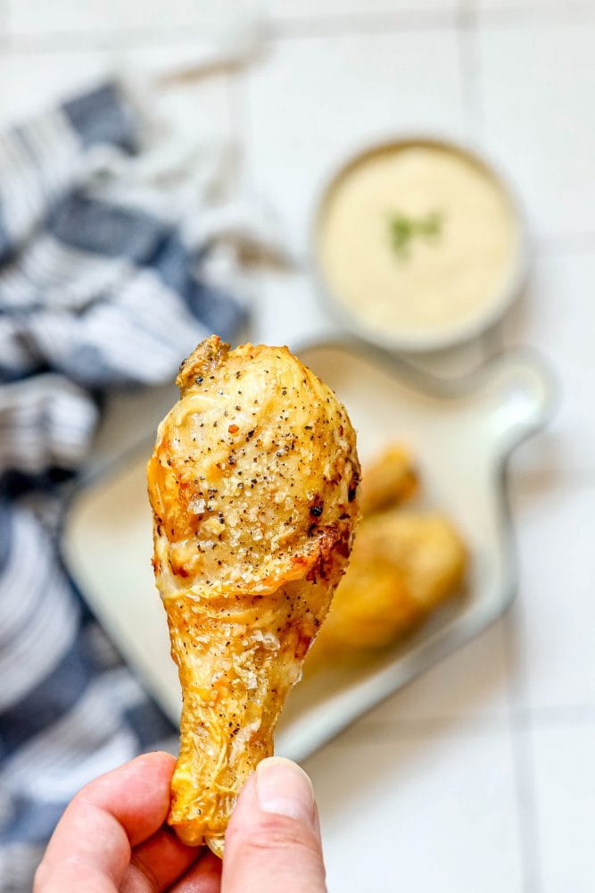 a hand holding baked chicken drumstick