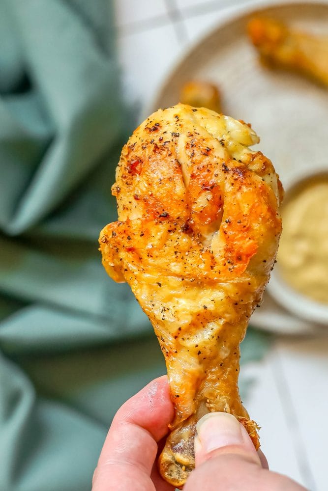 picture of a hand holding an air fried chicken drumstick 
