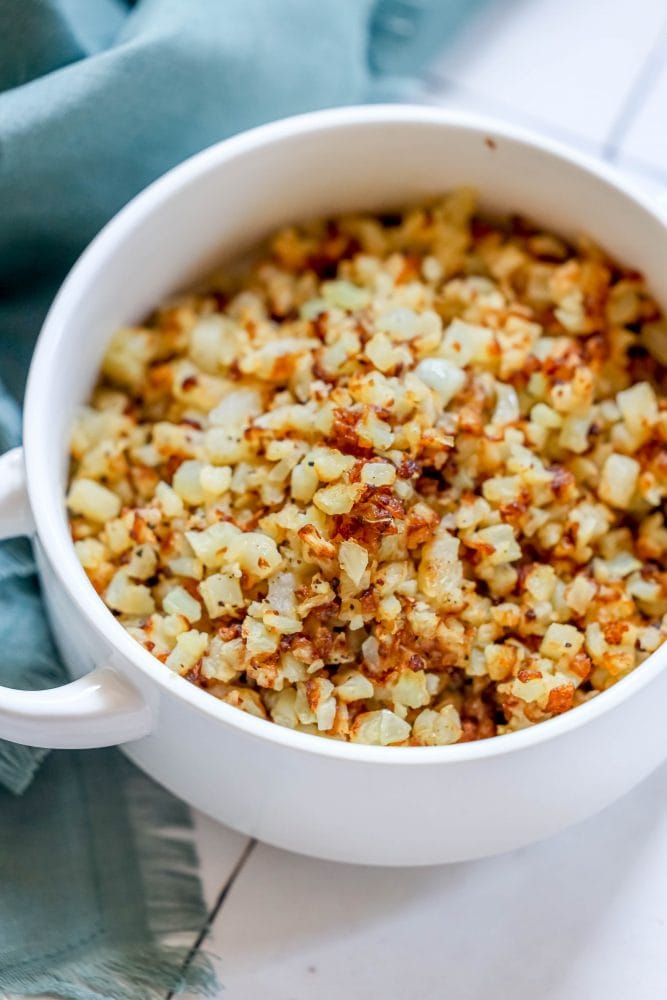 browned cauliflower rice in a white bowl.