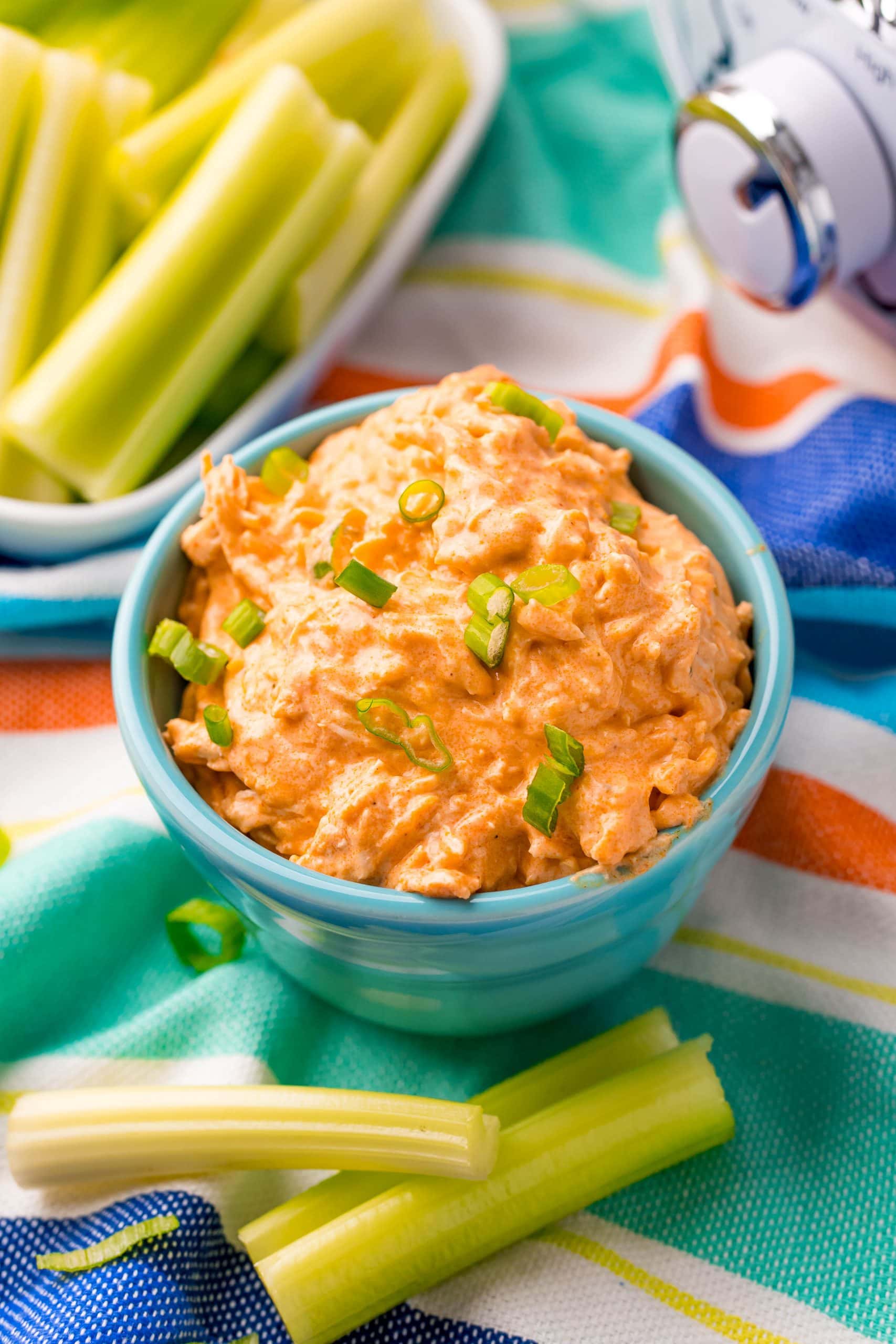 A bowl of buffalo chicken dip with celery and celery sticks, perfect for those looking for a keto-friendly option or using a slow cooker.