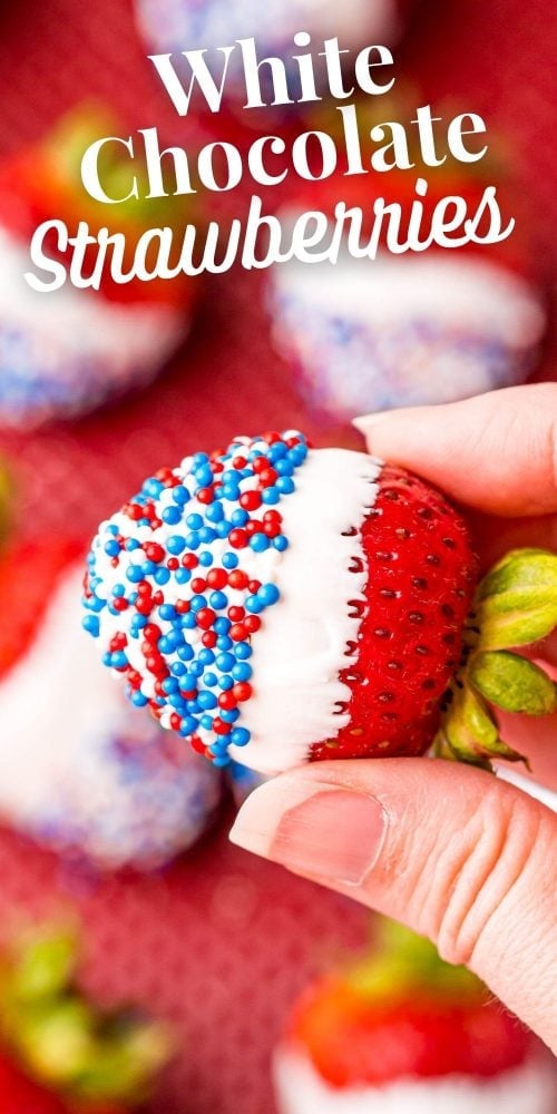 picture of a hand holding a strawberry dipped in white chocolate and covered in red white and blue sprinkles