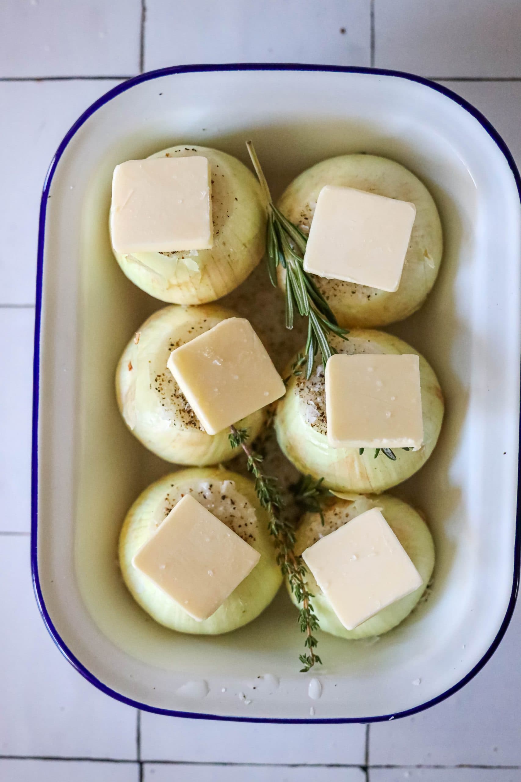 picture of onions in a baking dish with butter and thyme