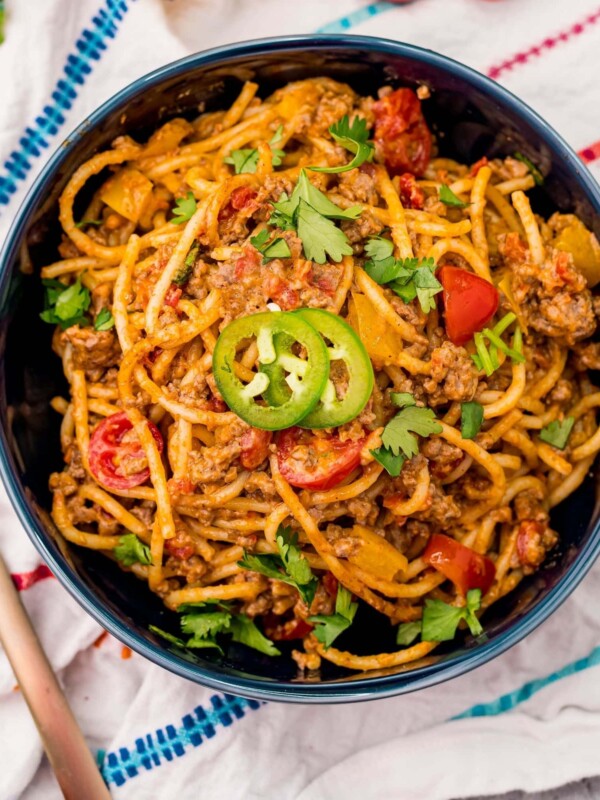 A bowl of Cheesy Taco Spaghetti with meat and tomatoes.