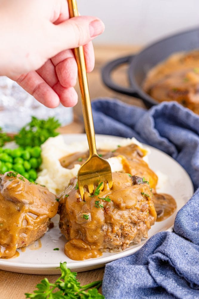 breaded steak with brown gravy and mashed potatoes on the side fork in it