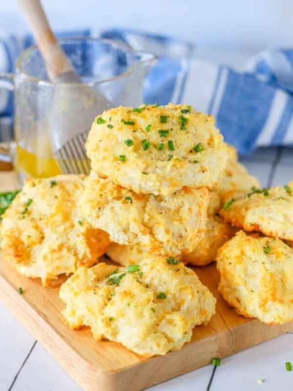 A stack of cheesy biscuits on a wooden cutting board.
