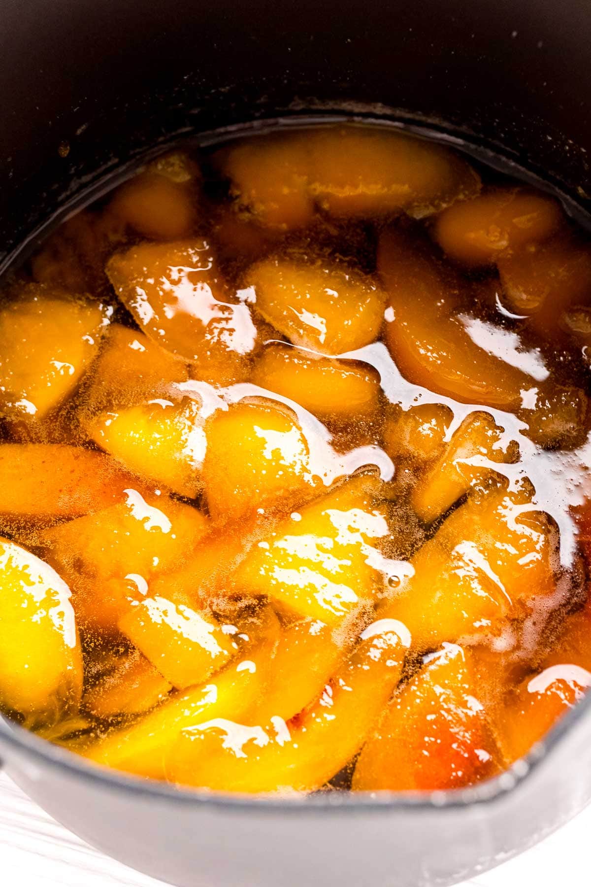 peaches cooking in a pot with water and sugar
