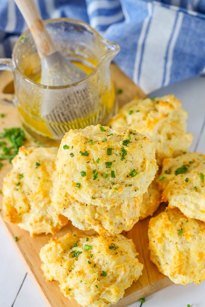 cheddar bay biscuits piled on top of each other on a cutting board